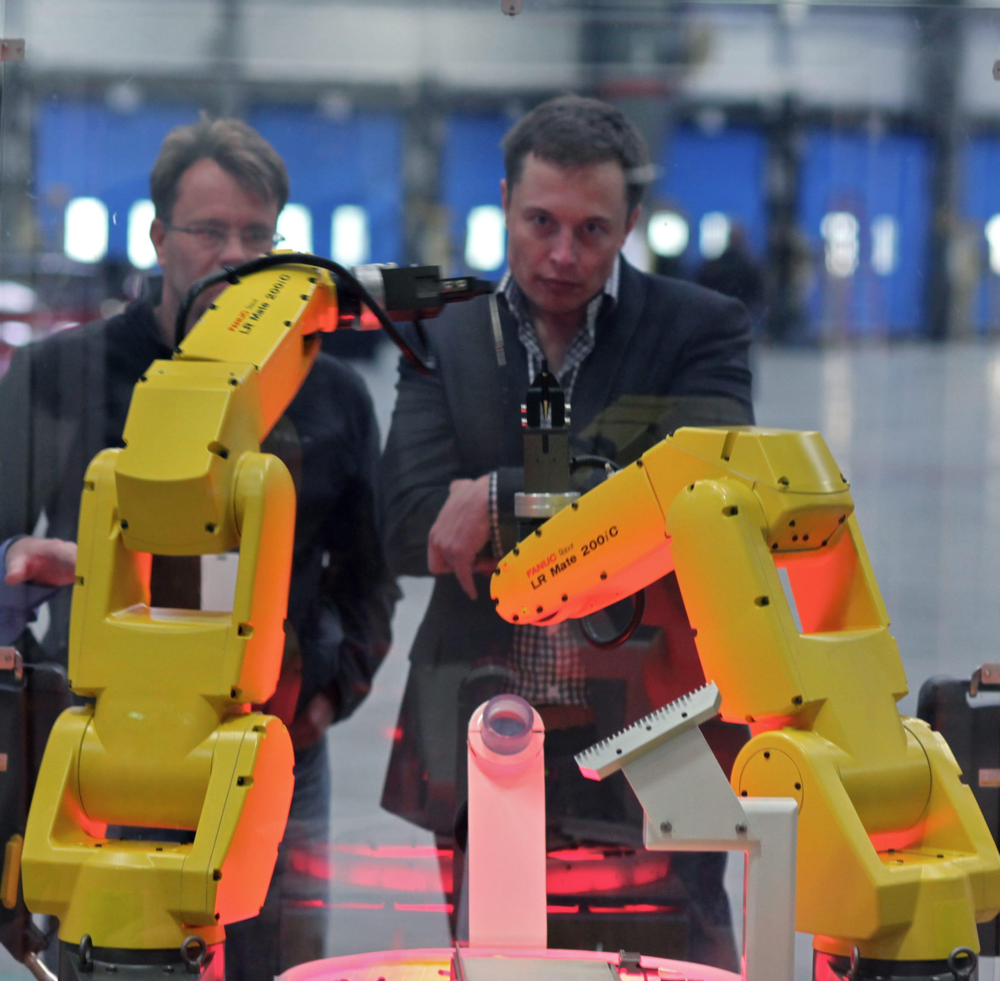 A person standing between two FANUC industrial robot arms on a factory floor
